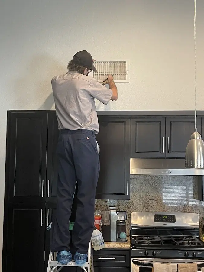Technician inspecting an air vent during HVAC service in Corinth